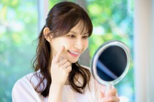 鏡の前で歯ぐきを気にしてチェックしている女性の写真